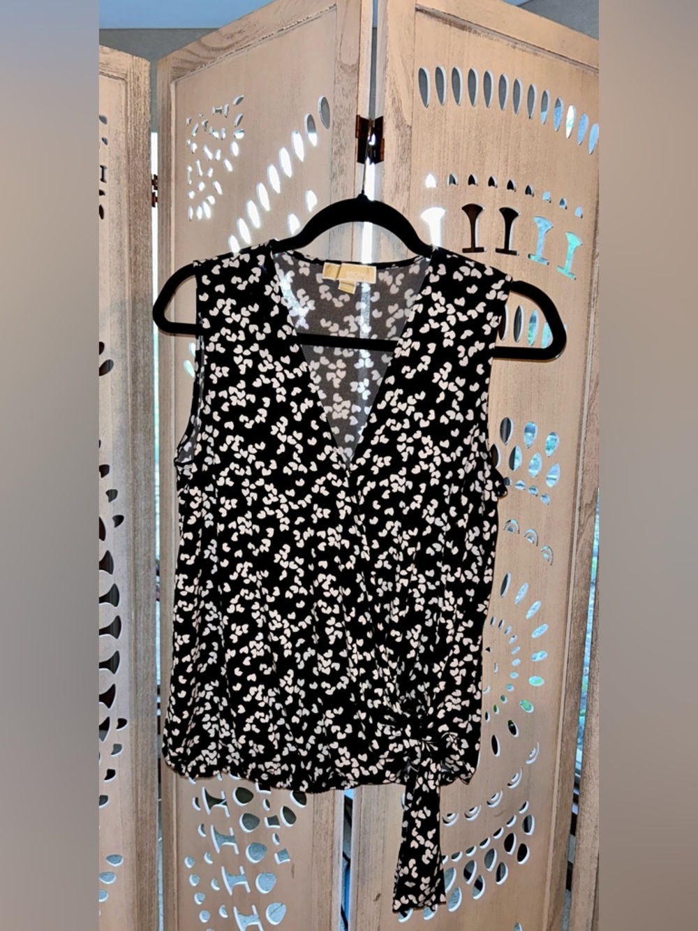 This Michael Kors top is a sleeveless wrap-style blouse